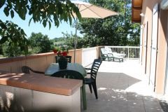 terrasse ensoleillée avec barbecue et salon de jardin